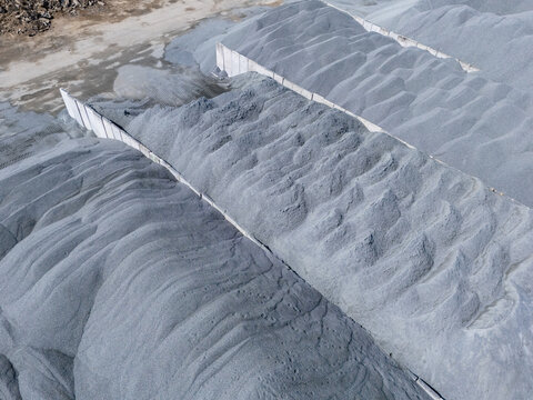 Aerial view of gravel piles at an asphalt plant separated by concrete walls in Gdansk, Poland.