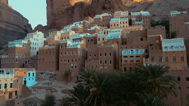 Aerial view of the historic mud-brick architecture of Al-Hajarayn village perched on a rocky cliff in Alhajrain, Hadhramaut Governorate, Yemen.