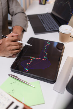 Professional trader analyzing stock market charts on laptop, tablet, and monitor while reviewing candlestick patterns, technical indicators, and market trends to support informed investment decisions.