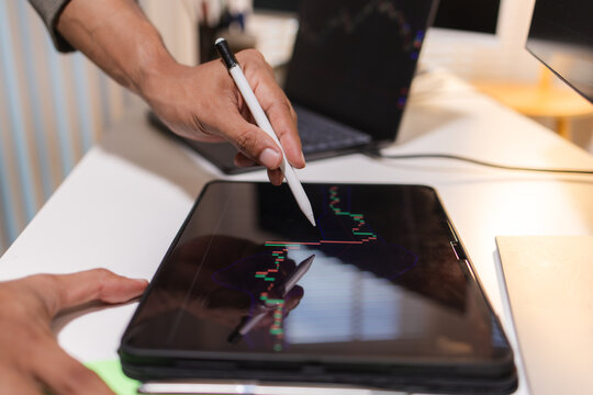 Professional trader analyzing stock market charts on laptop, tablet, and monitor while reviewing candlestick patterns, technical indicators, and market trends to support informed investment decisions.