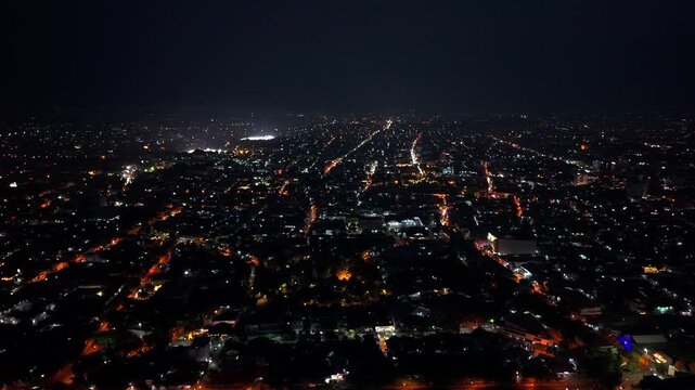 Aerial view of the illuminated Sheikh Zayed Grand Mosque Surakarta surrounded by the dense urban sprawl of Kecamatan Banjarsari, Jawa Tengah, Indonesia.