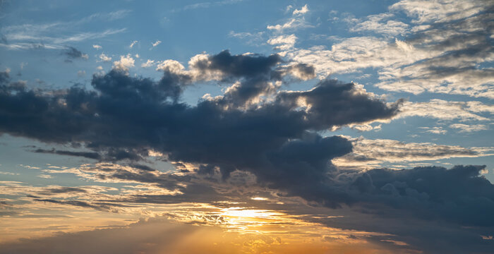 Dramatic Sunset Sky with Dark Cumulus Clouds and Golden Sun Rays.