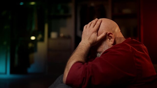 Lonely middle-aged man cries while sitting on floor, overwhelmed by despair