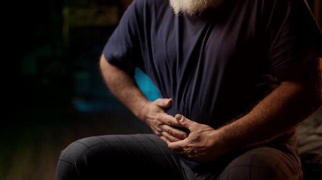 Unhappy bearded man in his 50s suffers from lower abdominal pain, inflammation