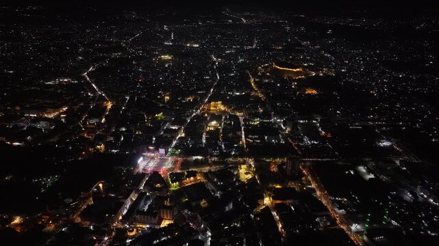 Aerial night view of an urban landscape in Syria featuring glowing city lights and illuminated streets.  Post-war Syrian cityscape and daily life at night.