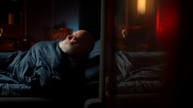 Tired bearded middle-aged man lies awake in bed, struggling with insomnia