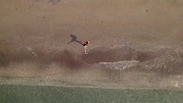 Aerial top view of a female boxer shadow fighting and training on a sandy beach by the sea