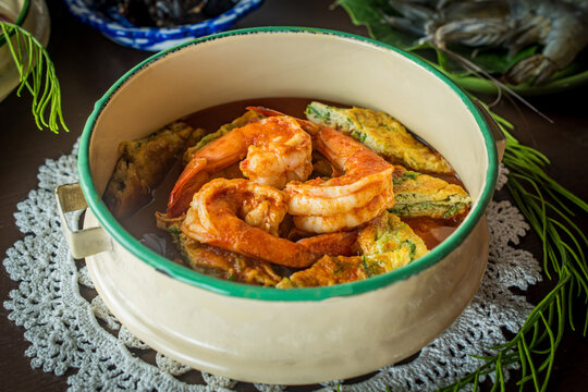 Traditional Thai sour curry with shrimp and acacia omelet in a vintage bowl, authentic Asian seafood cuisine. Gang Som Cha-om Goong