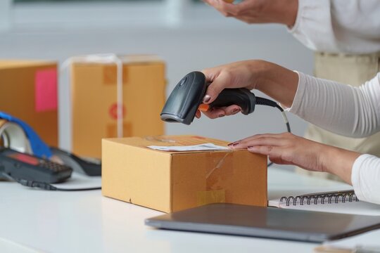 Close-up of hands using a barcode scanner to scan a package for shipping and logistics with shipping, delivery