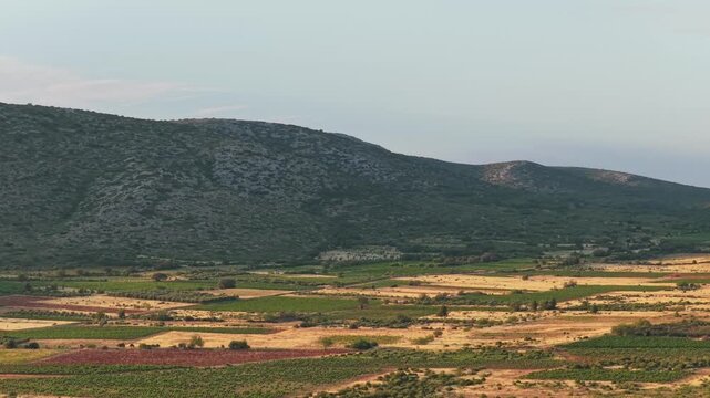 Agricultural fields and rolling hills in Opoul Perillos, France, with wind turbines visible on the hilltops.