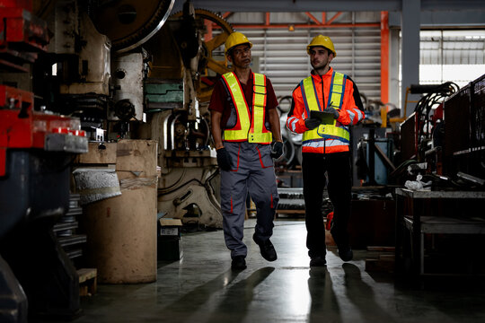 two professional engineer, worker, technician use clipboard discuss work, walk in steel metal manufacture factory plant industry. man and woman wear hard hat check quality machine. work, engineer,