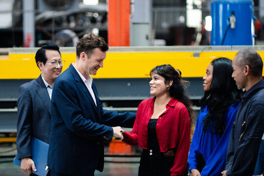 Business collaboration in manufacturing. Executives and factory professionals exchange a handshake during an industrial meeting. Partnership, teamwork, leadership, industry, collaboration