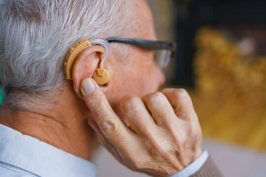 Close up of senior man with hearing aid, elderly male portrait indoors, assistive listening device, hearing support, healthcare concept and comfortable retirement lifestyle