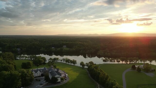 High aerial view over a lake, green countryside and rural buildings at sunset in the Shenandoah region of Virginia, with forested hills on the horizon.