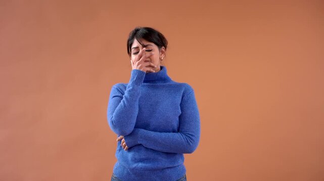 Girl speaks and expresses emotions in front of a plain background while wearing a blue sweater