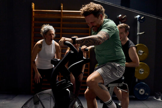 Men and women pushing through an intense group cycling workout with coach encouragement in gym