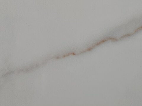 igh-resolution commercial stock background featuring polished white Calacatta marble with a subtle diagonal gold and brown mineral vein.