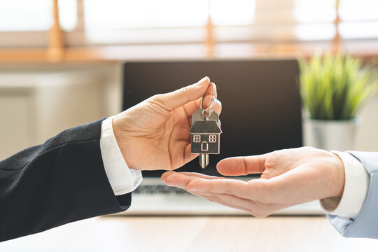 Close up agent giving a key to new owner or tenant, client after signed signature contract rental purchase, buyer apartment, home with landlord, realtor. Banker agreement mortgage loan. Property lease