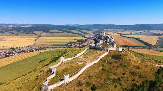 Hilltop castle near town. A view of a castle on a high hill in Slovakia with green fields and a small town nearby on a clear day.