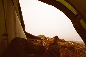 Fototapeta premium Camping view from inside tent with hiker resting outdoors