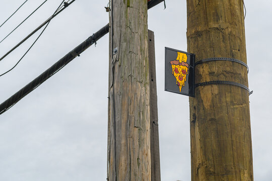 Small Sign with Image of Hand Holding a Slice of Pizza on a Utility Pole in New Orleans, LA, USA 
