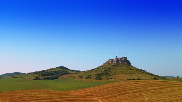 Mountain view with clear sky and fields. The picture shows a mountain with a flat top and green fields under a blue sky. The sun is shining bright.