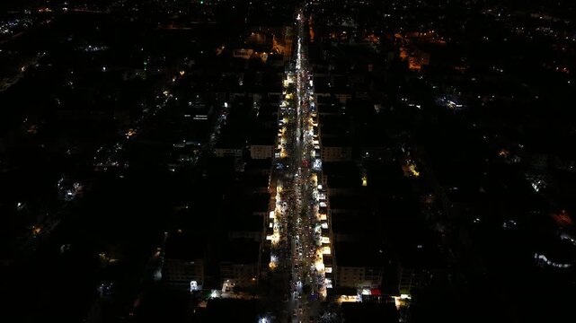 Aerial night view of an urban landscape in Syria featuring glowing city lights and illuminated streets.  Post-war Syrian cityscape and daily life at night.