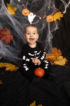 Baby in Skeleton Costume with Pumpkin and Leaves Halloween