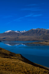 Fototapeta premium Lake Tekapo with snow-capped Southern Alps and dramatic blue sky, New Zealand