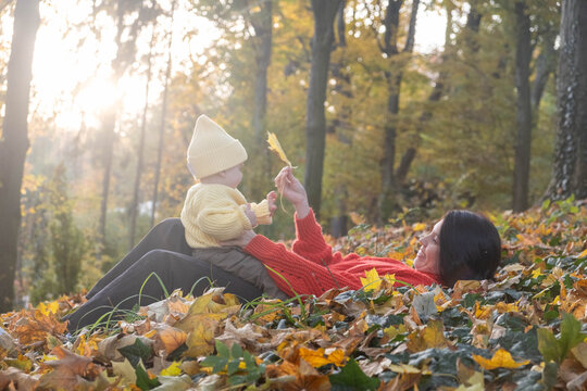 Mother and Baby Enjoying Autumn in Sunlit Forest Copy Space