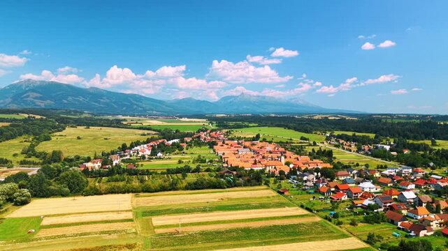 Scenic view of a village with mountains. A village is seen from above with houses and fields. Mountains stand in the background under a clear sky.