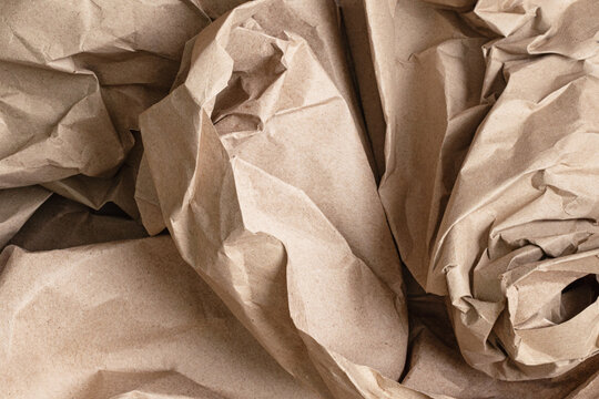 Crumpled kraft paper texture with natural brown tones, wrinkles and folds, creating a rustic organic background for packaging, crafts and design.