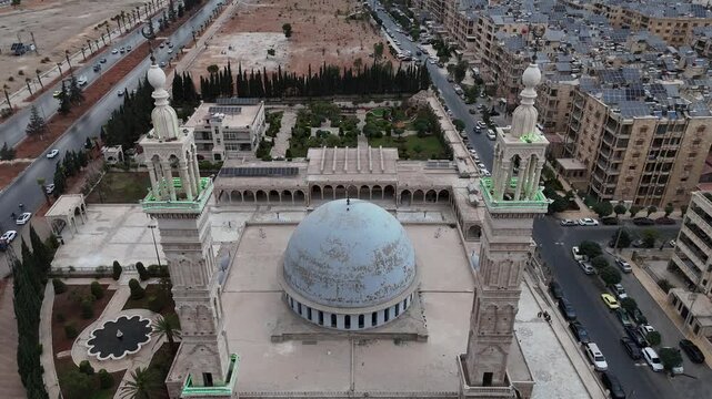 Aerial drone view of an Islamic mosque featuring a prominent dome and tall minarets. Concept of world religions, faith, and Islamic culture in post-war Syria.