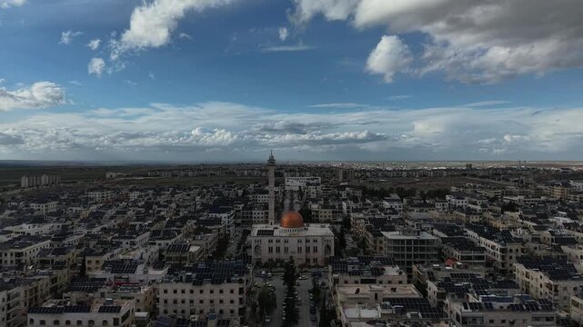 Aerial drone view of an Islamic mosque featuring a prominent dome and tall minarets. Concept of world religions, faith, and Islamic culture in post-war Syria.