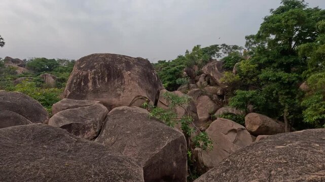 A wide shot capturing the iconic granite rock formations of Mama Bhagne Pahar in Dubrajpur, Birbhum, West Bengal. The footage showcases massive natural boulders surrounded by green trees and foliage 