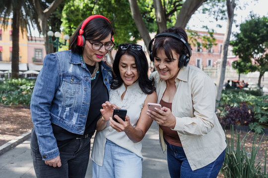 latin senior friends listening music in public park in Mexico Latin America, mexican middle age females having fun outdoors
