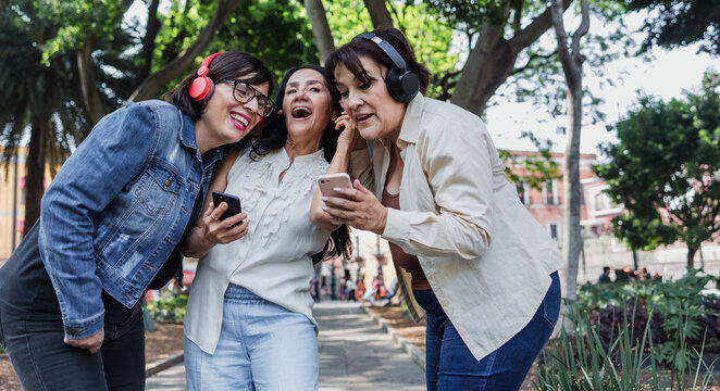 latin senior friends listening music in public park in Mexico Latin America, mexican middle age females having fun outdoors