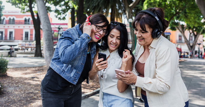 latin senior friends listening music in public park in Mexico Latin America, mexican middle age females having fun outdoors
