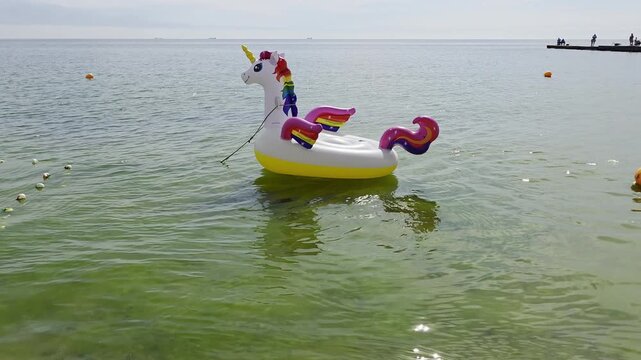 Inflatable unicorn float floating on sea water near beach