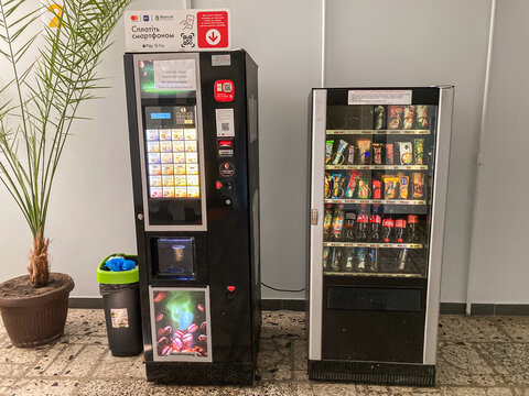 Vending machine black, digital screen with snacks and drinks, refrigerator silver, stocked, coin slot, beverages various bottles, trash bin green, indoor set - Kyiv, Ukraine 07-15-2025