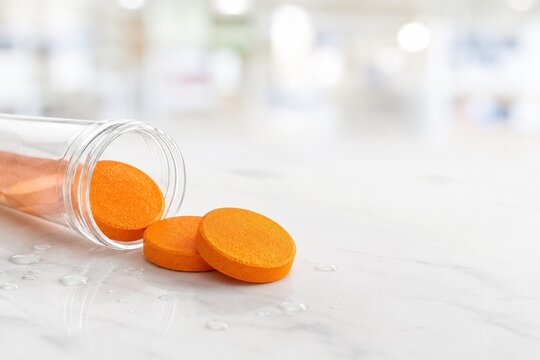 Pastillas de color naranja ca&iacute;das de un frasco en una superficie