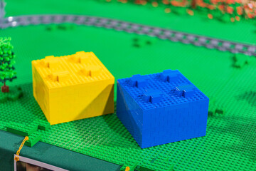 Fototapeta premium Lego train set with two houses, one yellow and the other blue, on a green base - Kyiv, Ukraine - June 7, 2025