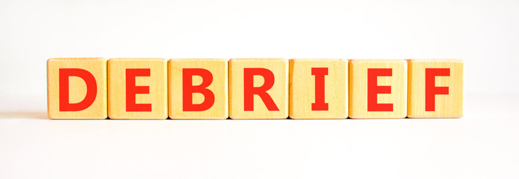 Debrief word symbol. Concept word Debrief on beautiful wooden blocks. Beautiful white table white background. Business debrief word concept. Copy space.