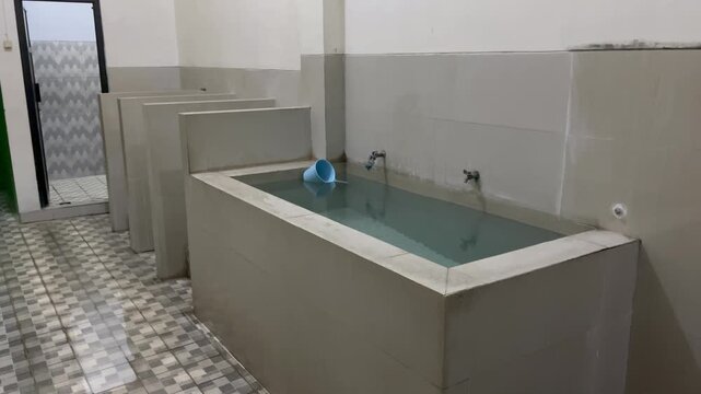 Row of shared bath stalls with tiled water reservoirs