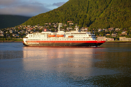 Tromso, Norway, June 19th 2026: A Hurtigruten ship lies alongside the harbor in Troms&oslash;, with the striking Arctic Cathedral rising across the water, capturing the unique blend of maritime heritage	