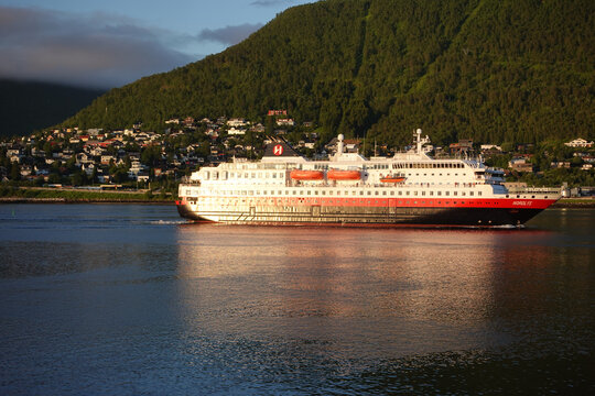 Tromso, Norway, June 19th 2026: A Hurtigruten ship lies alongside the harbor in Troms&oslash;, with the striking Arctic Cathedral rising across the water, capturing the unique blend of maritime heritage	