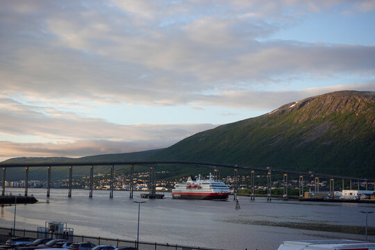 Tromso, Norway, June 19th 2026: A Hurtigruten ship lies alongside the harbor in Troms&oslash;, with the striking Arctic Cathedral rising across the water, capturing the unique blend of maritime heritage	