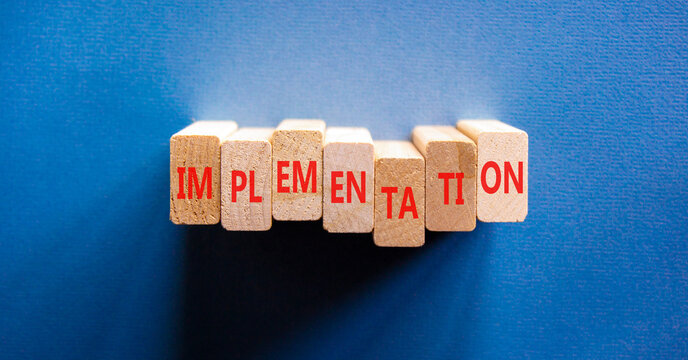 Implementation word symbol. Concept word Implementation on beautiful wooden blocks. Beautiful blue background. Business implementation word concept. Copy space.