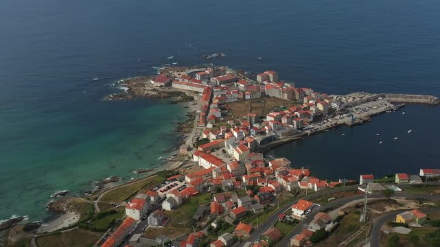 Aerial view of the coastal town of Caion with its harbor, red-roofed houses, and rocky shoreline along the Atlantic Ocean in Caion, A Coruna, Spain.