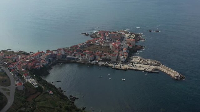 Aerial view of the coastal village of Caion with its harbor, small boats, and traditional houses along the rocky shoreline in Caion, A Coruna, Spain.